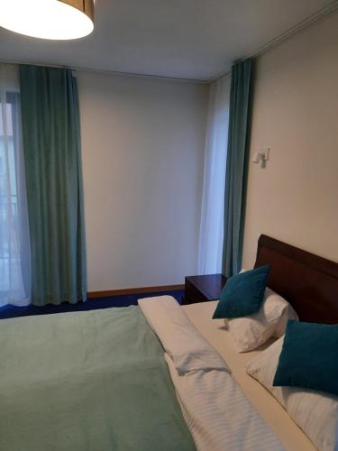 1 dormitorio con 1 cama y una ventana con cortinas verdes en Azymut en Jarosławiec