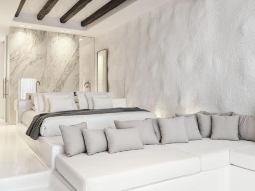 a white bedroom with a bed and two white couches at Mykonos Earth Suites in Mýkonos City