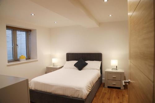 a bedroom with a bed with two night stands and two lamps at Letting Serviced Apartments - Sheppards Yard, Hemel Hempstead Old Town in Hemel Hempstead