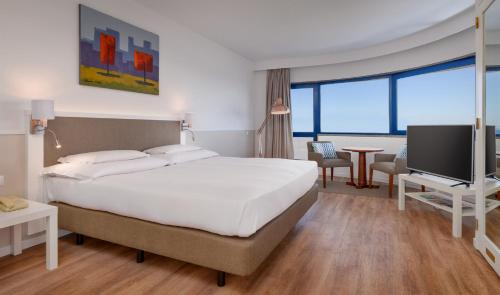 um quarto com uma grande cama branca e uma televisão em Hotel Pestana Cascais Ocean & Conference Aparthotel em Cascais