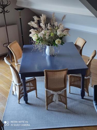 a blue dining room table with chairs and a vase of flowers at Un brin de Paradis "appartement de 100 m²" in Harzé
