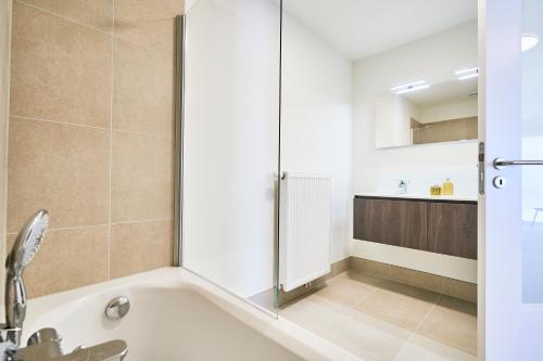 a bathroom with a tub with a shower and a sink at Diamant 2BR in Brussels
