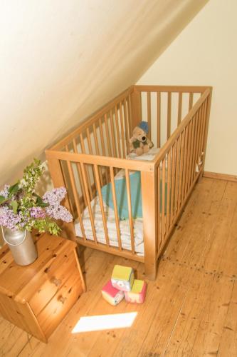 a crib with a teddy bear and toys in a room at Landhotel & Reiterhof Schumann in Triptis