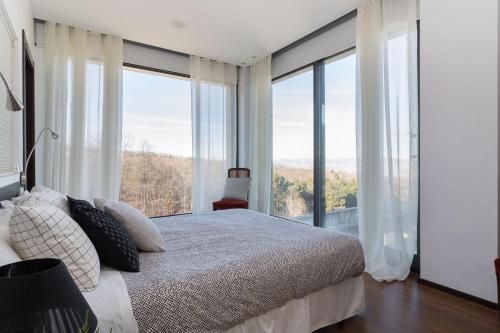 a bedroom with a bed and large glass windows at El Soto de Sojuela Luxury Chalet, Golf&Bosque in Sojuela
