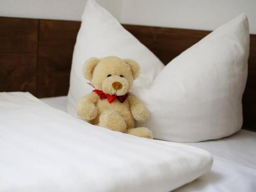 a teddy bear sitting on a bed with pillows at Landhotel & Reiterhof Schumann in Triptis