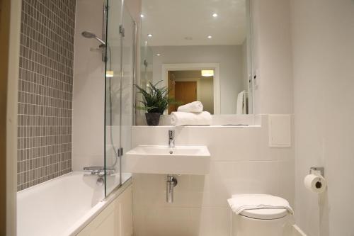 ein Badezimmer mit Waschbecken, Toilette und Spiegel in der Unterkunft Letting Serviced Apartments - Central St Albans in St Albans