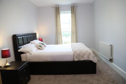 a bedroom with a large bed and a window at Letting Serviced Apartments - Central St Albans in St. Albans