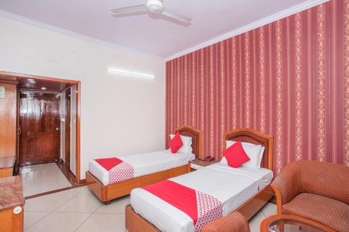 a hotel room with two beds and a chair at Hotel Chetan International in Bengaluru