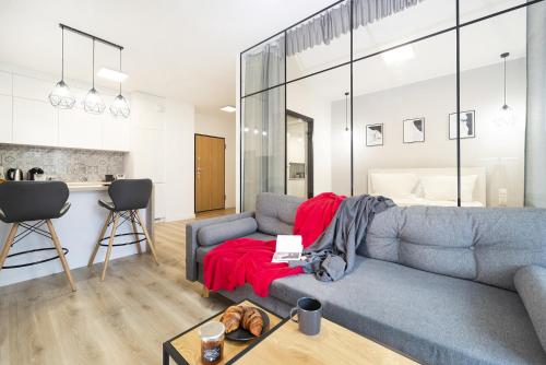 sala de estar con sofá gris y manta roja en Browar Gdański by Renters en Gdansk