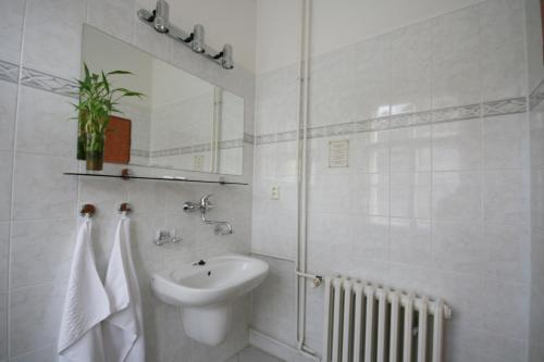 a white bathroom with a sink and a mirror at Penzion Loreta in Luhačovice