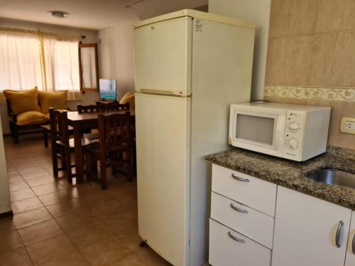 Una cocina con un refrigerador blanco y un microondas. en Acuarela, en Villa Gesell