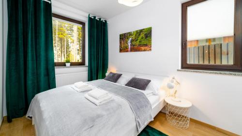 a bedroom with a white bed with green curtains at HELLO Apartament z ogrodem - Alpina in Karpacz