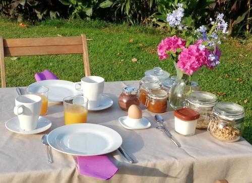 einen Tisch mit Teller mit Lebensmitteln und eine Vase mit Blumen in der Unterkunft Domaine de la Castagnère in Castetnau-Camblong