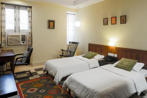 a bedroom with two beds and a desk and a table at Magpie Villa in Jaipur