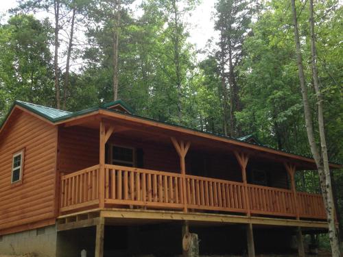 a log cabin with a deck in the woods at Avenwood Cabins in Logan
