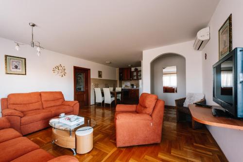 a living room with orange furniture and a tv at Irish House Međugorje in Međugorje