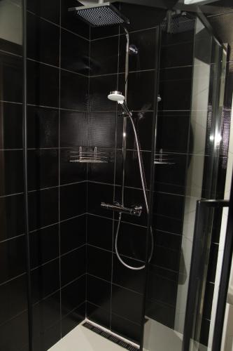 a bathroom with a shower with black tiles at Купецький Двір in Mizhhirʼʼya