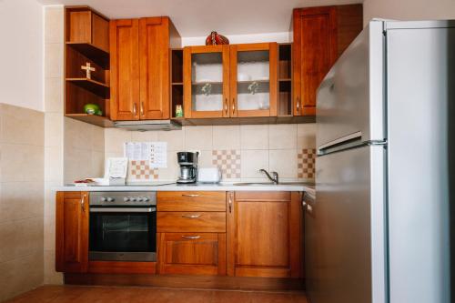 a kitchen with wooden cabinets and a stainless steel refrigerator at Irish House Međugorje in Međugorje
