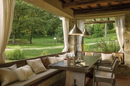 a porch with a couch and a table with wine glasses at Ciliegia in Roccalbegna
