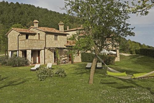 a house with a tree and a hammock in the yard at Ciliegia in Roccalbegna