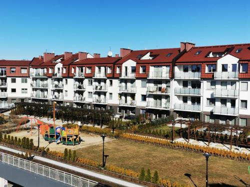 un gran edificio de apartamentos con un parque infantil delante de él en Greta, en Świnoujście