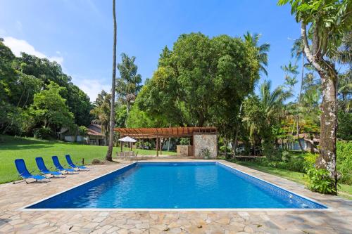 a swimming pool with blue chairs and trees at Vila Siriúba Hotel in Ilhabela