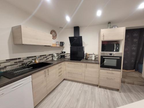 - une cuisine avec des placards en bois et des appareils noirs dans l'établissement Gîte du ruisseau, à Nissan-lez-Enserune