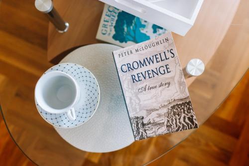 a book and a cup of coffee on a glass table at Irish House Međugorje in Međugorje