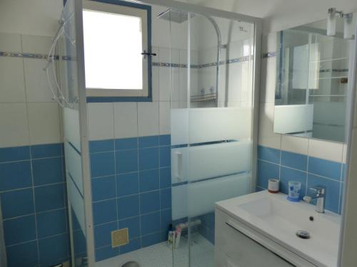uma casa de banho azul e branca com um lavatório e um chuveiro em Appartement Pour 6 Personne- Residence San Michele em Hossegor