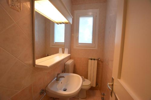 a bathroom with a sink and a toilet and a window at Villa a Lignano Pineta in Lignano Sabbiadoro