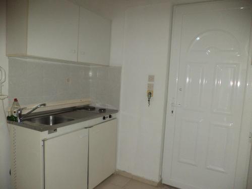 een keuken met een wastafel en een witte deur bij White Palace Pavlos apartment1 in Faliraki