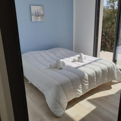 un grand lit blanc dans une chambre avec une fenêtre dans l'établissement Villa L'Arbousier 4 pers piscine chauffée 2 min plage en voiture, à Sainte-Lucie de Porto-Vecchio