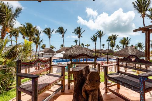 a resort with a pool and benches and palm trees at Acquapipa Resort in Pipa