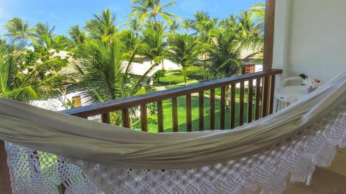 a hammock on a balcony with palm trees at Acquapipa Resort in Pipa