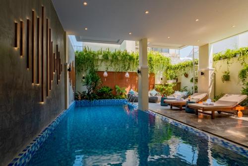een zwembad in een huis met een patio bij Hoi An Merrily De Art Hotel in Hội An