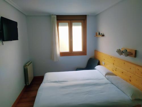 a bedroom with a white bed and a window at Pensión Urkia in Donostia-San Sebastián