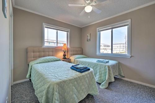 a bedroom with two beds and two windows at Condo with Balcony and Pool Walk to 2 Beach Accesses! in Carolina Beach