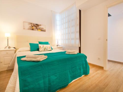 una camera da letto con un letto verde e asciugamani di Apartment Oiza Classic, at Alcudia Beach a Port d'Alcudia