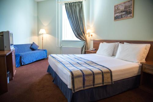 Habitación de hotel con cama y silla en Petro Sport Hotel, en San Petersburgo