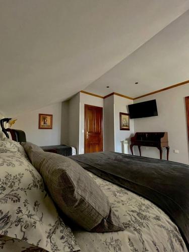 ラス・アレーナス・デ・カブラレスにあるHotel Rural El Torrejonの大きなベッドとピアノのある寝室