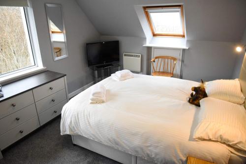 a bedroom with a white bed with a stuffed animal on it at 5 Glenconon Bed and Breakfast in Uig