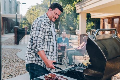 a man is cooking food on a grill at Candlewood Suites Belle Vernon by IHG in Belle Vernon