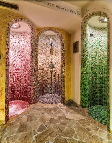 une salle de bain avec douche aux carreaux rouges et verts dans l'établissement Leading Relax Hotel Maria, à Moena