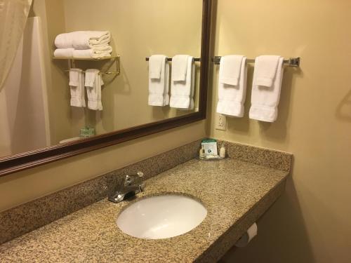 y baño con lavabo, espejo y toallas. en Cobblestone Inn & Suites - Durand, en Durand