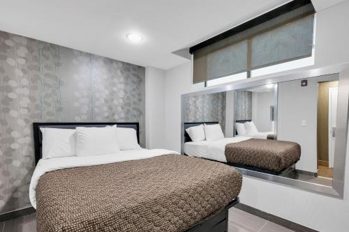 a bedroom with two beds and a mirror at Hotel Mint JFK Airport in Queens