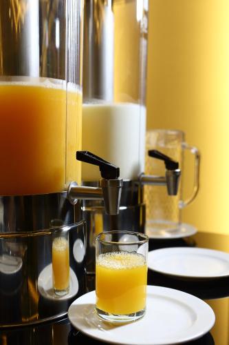 a glass of orange juice on a plate next to a juicer at De Chai Oriental Nimman - SHA Plus in Chiang Mai