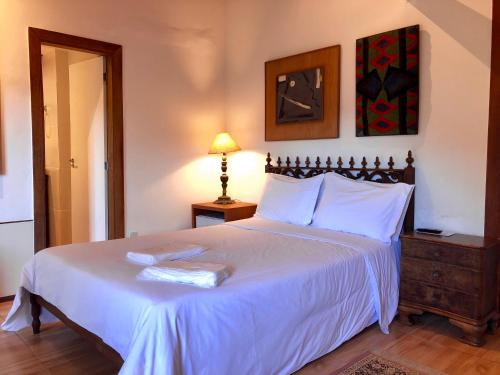 a bedroom with a large bed with white sheets and a lamp at Pousada Pataca de prata - Pousada de Época in Petrópolis