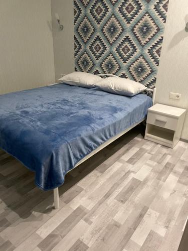 a bed with a blue blanket and a wall at Apartment Riviera in Fontanka