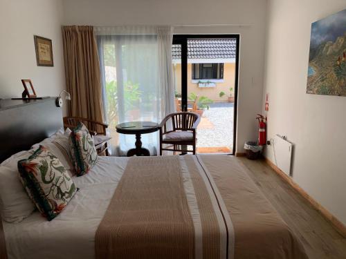 a bedroom with a bed with a table and a window at Private room in Ambiente Guest House in Knysna