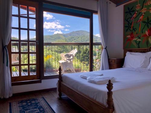 a bedroom with a bed and a large window at Pousada Pataca de prata - Pousada de Época in Petrópolis